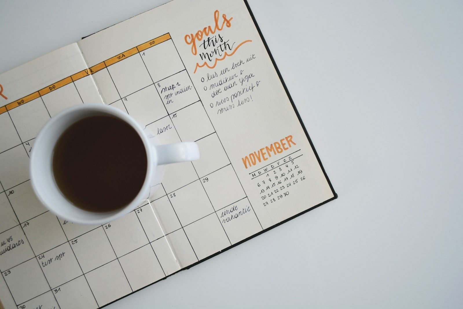 Agenda mensuel ouvert avec une tasse de café, pour organiser les vacances scolaires