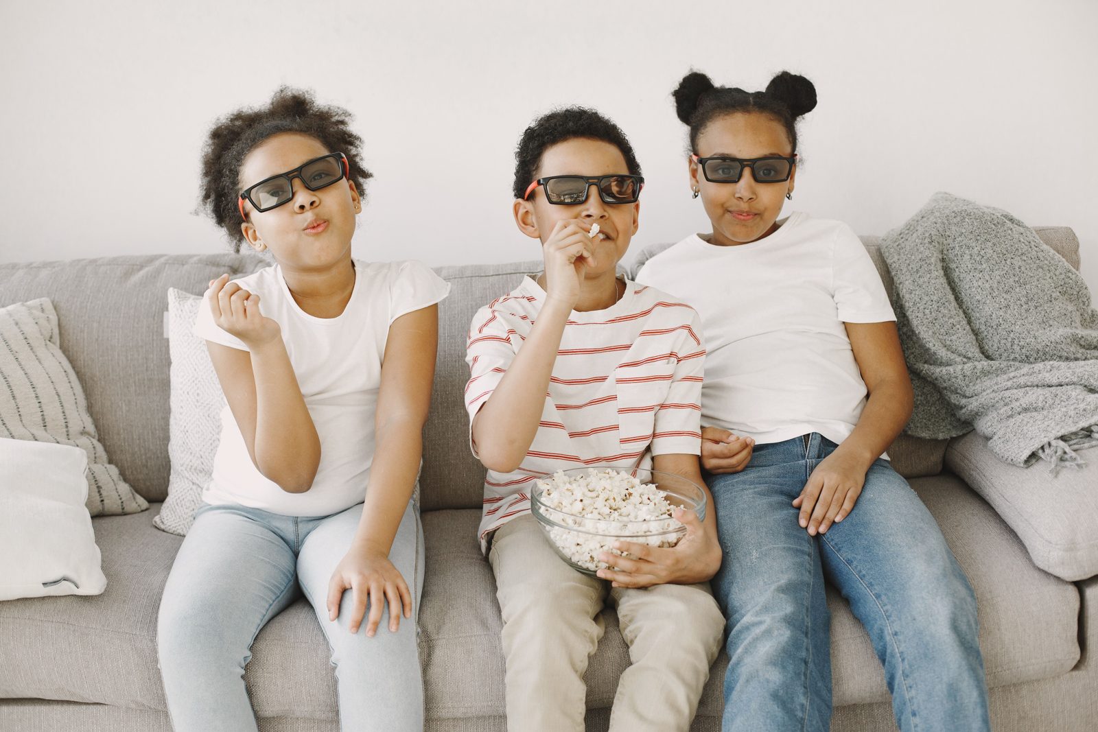 Trois enfants avec des lunettes 3D et du pop-corn devant un film