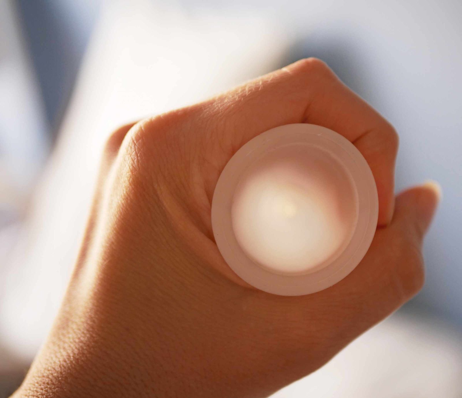 Coupe menstruelle réutilisable en silicone tenue dans une main, vue de dessus.