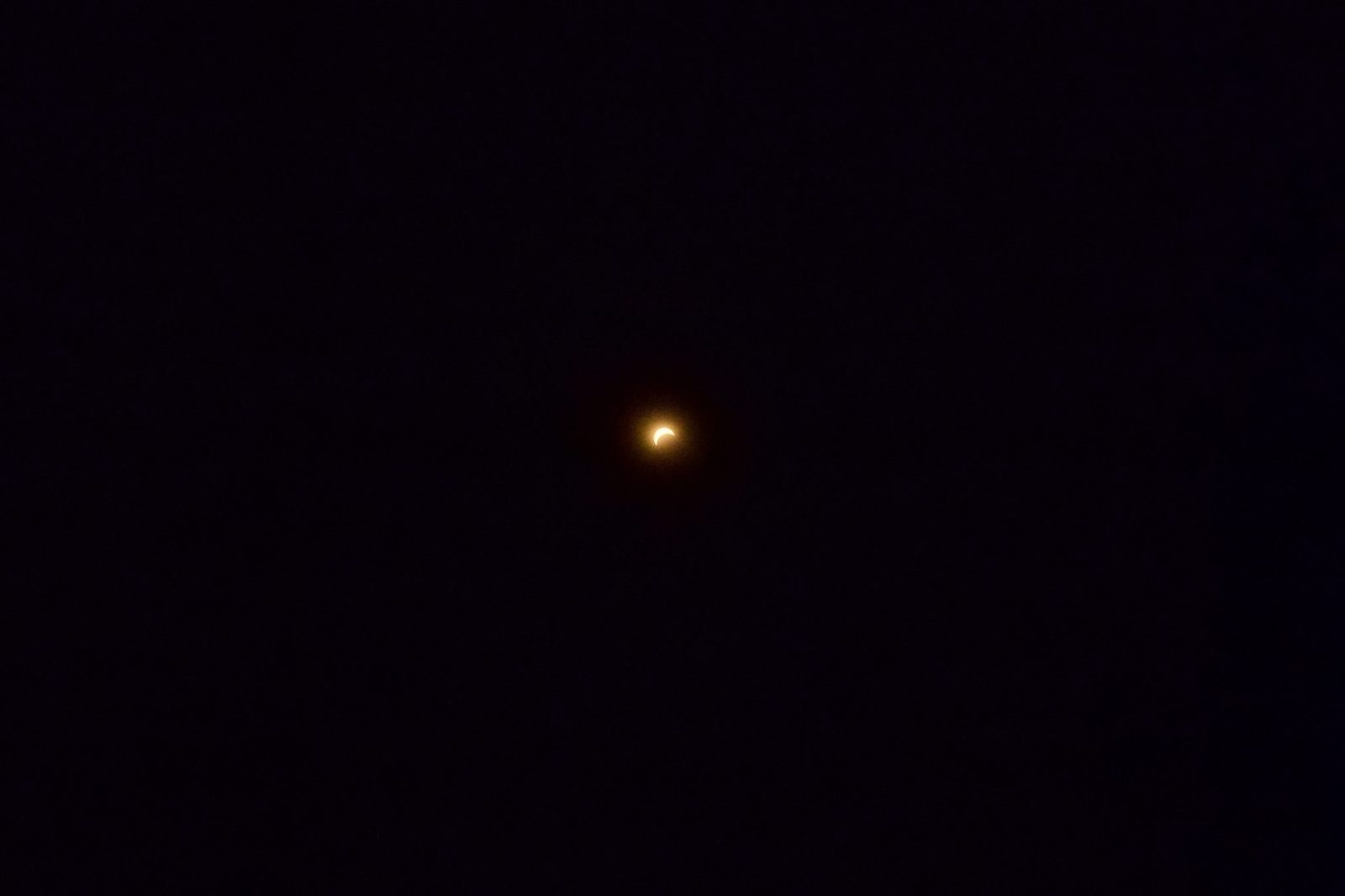 Photographie d'une éclipse solaire partielle : le Soleil réduit à un fin croissant lumineux dans un ciel sombre.