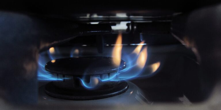 Bruleur de gaziniere allume, flamme bleue, illustrant le cout du gaz naturel pour cuisiner et se chauffer.