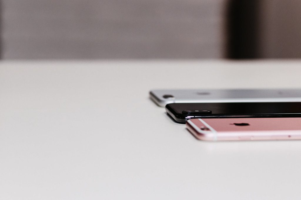 Trois smartphones posés côte à côte, illustrant le téléphone portable des élèves visé par la règle scolaire.