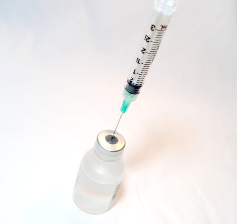 Une seringue et un flacon de vaccin posés côte à côte sur fond neutre.