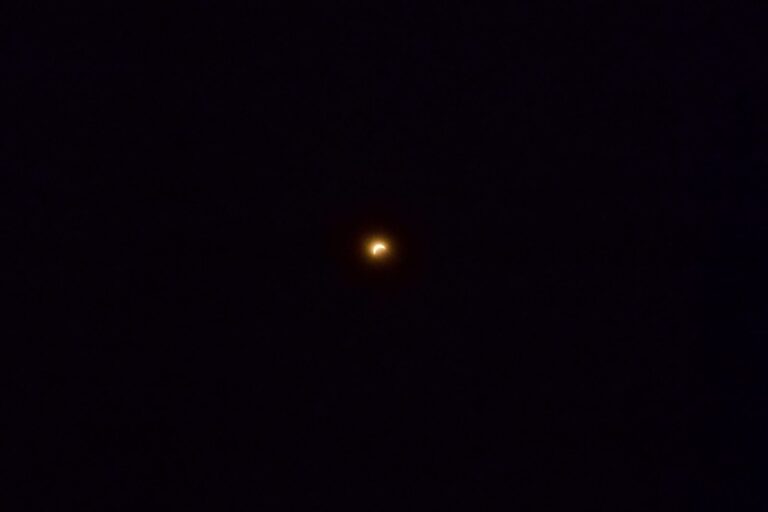 Photographie d'une éclipse solaire partielle : le Soleil réduit à un fin croissant lumineux dans un ciel sombre.