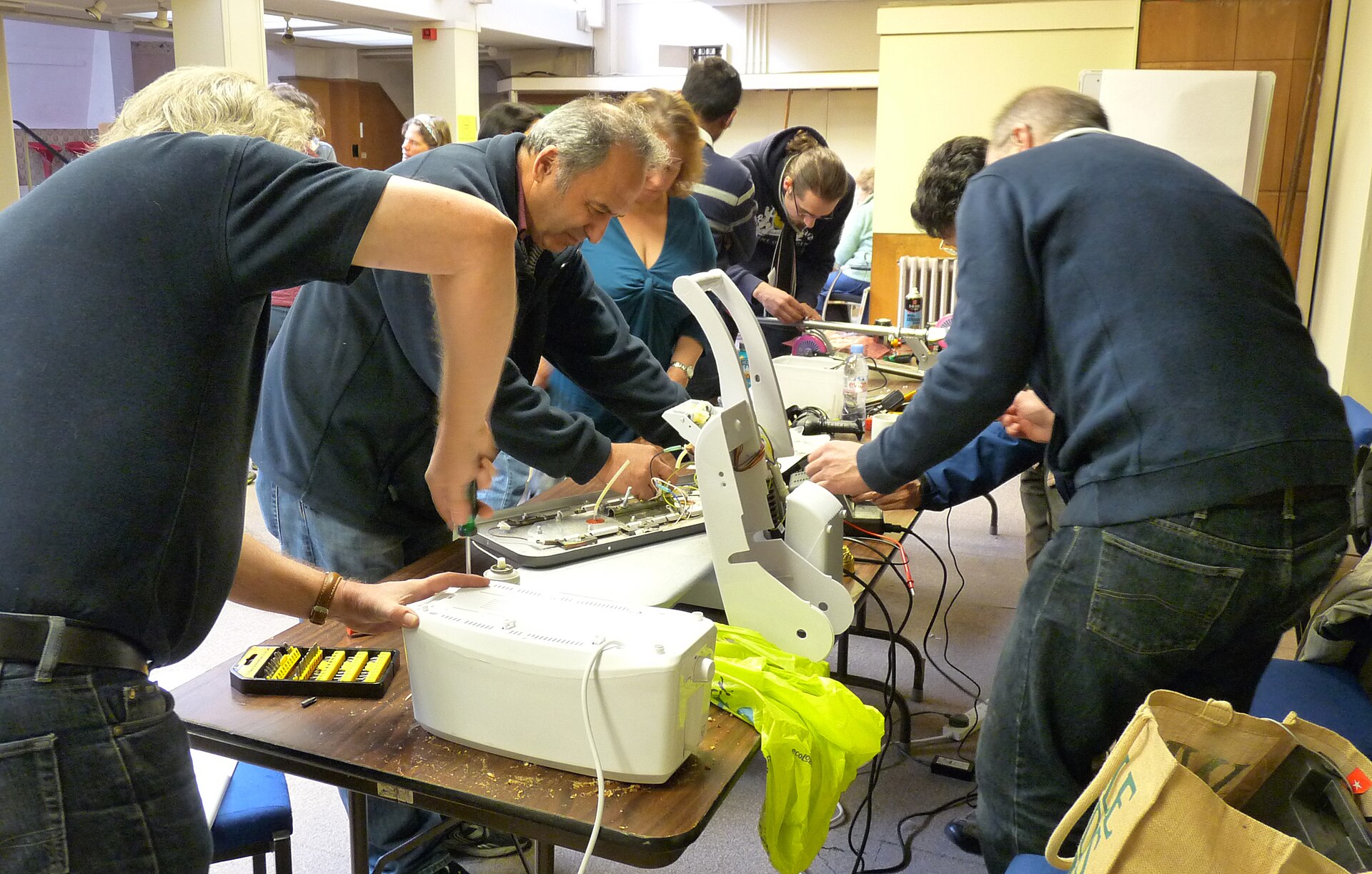 Des participants démontent un appareil électroménager autour d'une table lors d'un atelier de réparation.