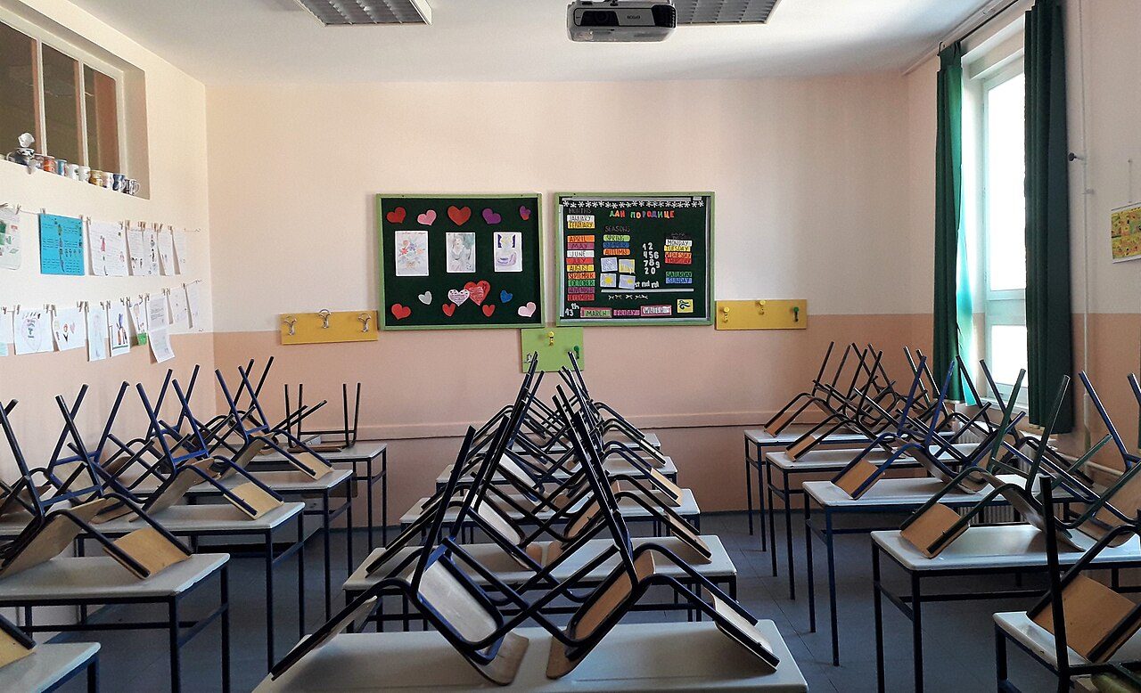 Salle de classe d'école primaire, avec des dessins d'élèves affichés au mur.