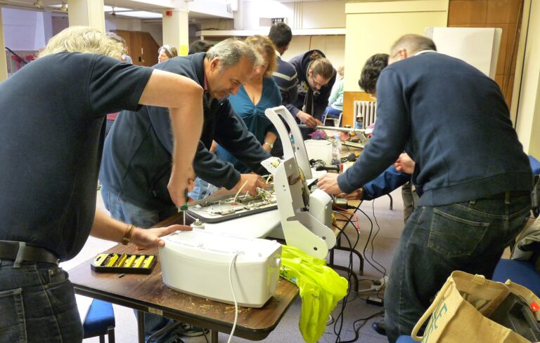 Des participants démontent un appareil électroménager autour d'une table lors d'un atelier de réparation.