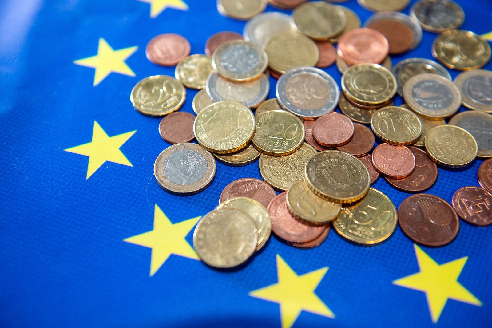 Des pieces de monnaie en euros posees sur un drapeau europeen.