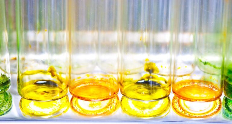 Gros plan sur des tubes a essai de laboratoire contenant des liquides colores jaunes, orange et verts.