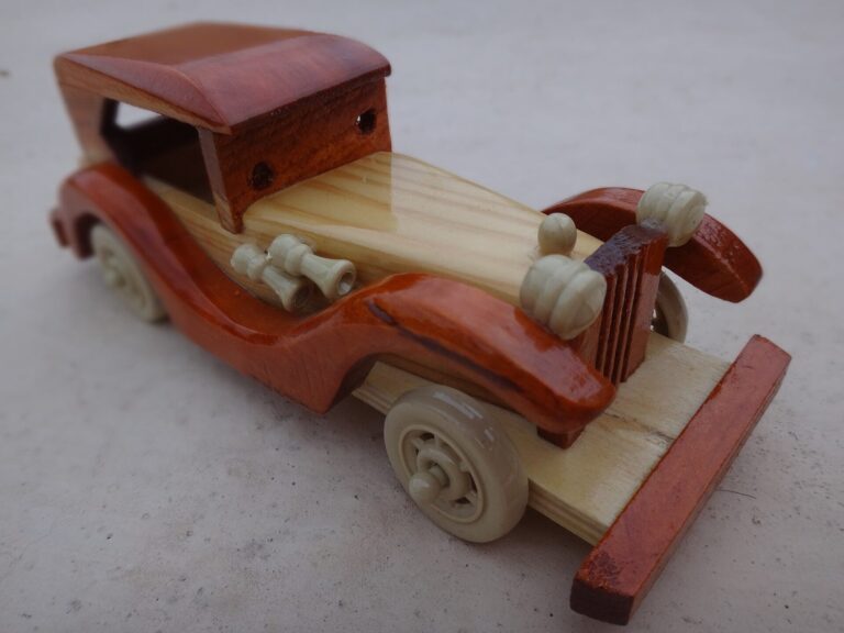 Petite voiture ancienne en bois, jouet artisanal pose sur une surface claire.
