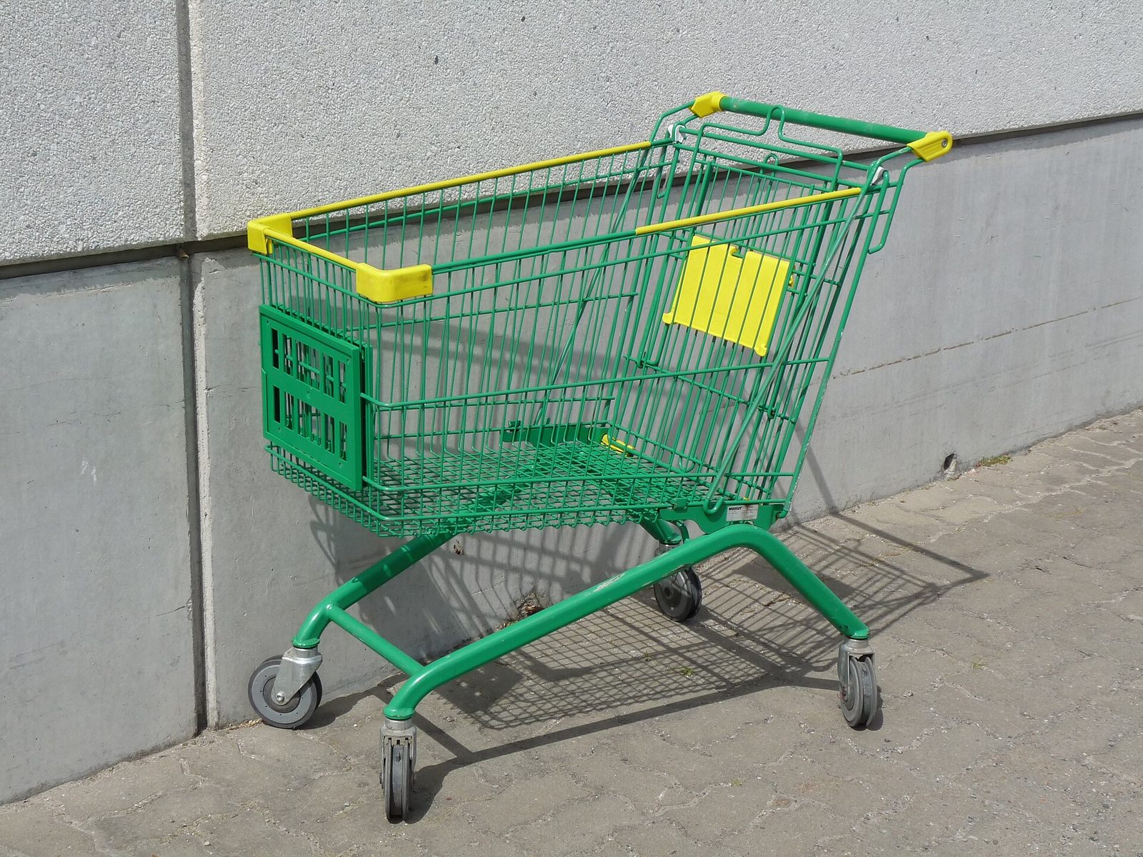 Un chariot de supermarche vide, stationne devant un magasin : illustration des courses alimentaires.