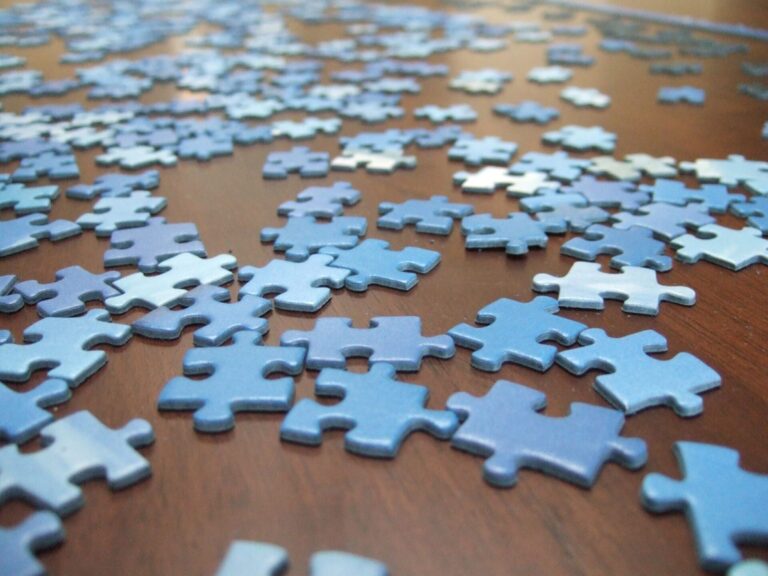 Pièces de puzzle bleues éparpillées sur une table en bois, prêtes à être assemblées