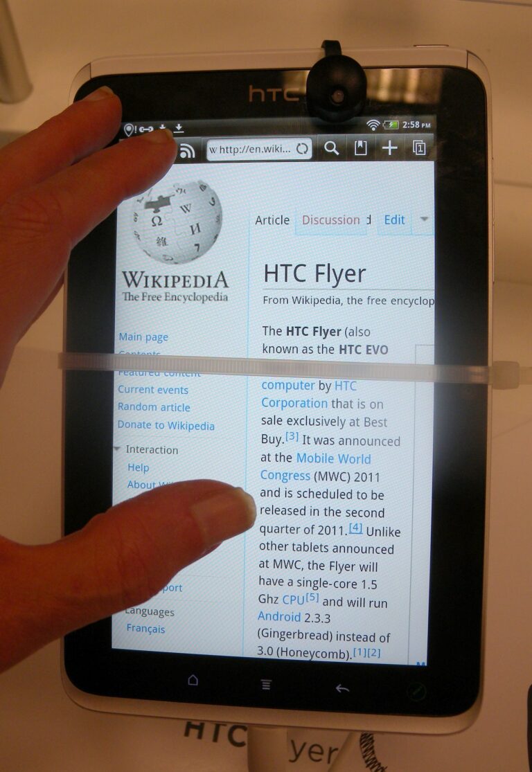 Une tablette tactile tenue en main, affichant une page d'encyclopédie en ligne.